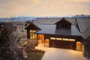 Rustic home with stone siding, a metal roof, a garage, and a mountain view