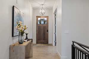 Foyer entrance with light wood-style flooring and a chandelier