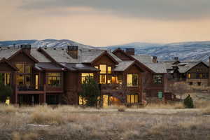 Back of property featuring a chimney, a mountain view, and stone siding