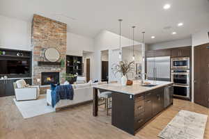 Kitchen with dark brown cabinetry, a breakfast bar area, an island with sink, pendant lighting, and built in appliances