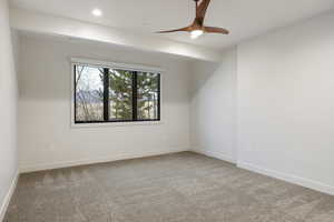Empty room featuring light colored carpet and a ceiling fan