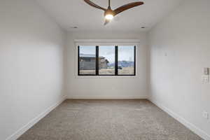 Spare room featuring light colored carpet and a ceiling fan