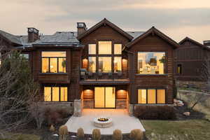 Rear view of property featuring an outdoor fire pit, a balcony, a chimney, stone siding, and a patio