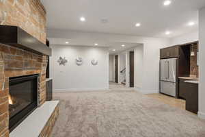 Unfurnished living room featuring light carpet, recessed lighting, a large fireplace, and stairway