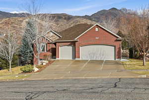 View of front of house featuring a mountain view, driveway, brick siding, and a garage