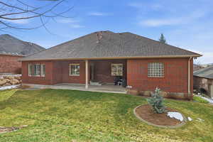 Rear view of property featuring a patio, a yard, brick siding, and roof with shingles