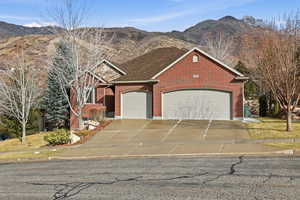 View of front facade featuring a mountain view, a garage, driveway, and brick siding