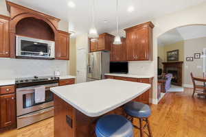Kitchen with appliances with stainless steel finishes, decorative light fixtures, a breakfast bar area, tasteful backsplash, and arched walkways