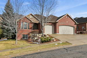 View of front of home featuring driveway, brick siding, a garage, and a front yard