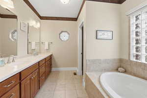Full bathroom with double vanity, a bath, healthy amount of natural light, and light tile patterned floors