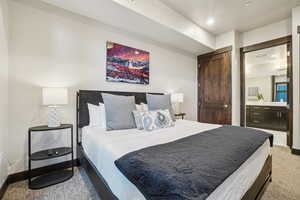 Bedroom with light colored carpet, connected bathroom, and recessed lighting
