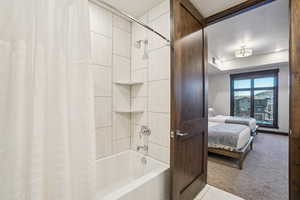 Bathroom with shower / bath combo, ensuite bath, light carpet, light tile patterned flooring, and a raised ceiling