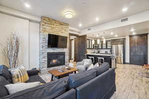 Living area with a stone fireplace, light wood finished floors, and recessed lighting