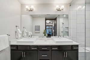 Full bath with a stall shower, double vanity, and ensuite bath