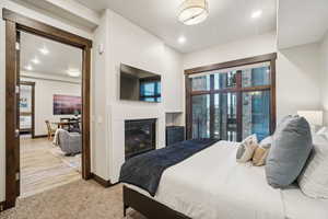 Bedroom featuring a glass covered fireplace, carpet floors, and recessed lighting