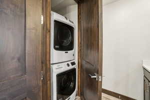 Laundry room featuring stacked washing machine and dryer and baseboards
