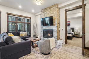 Living room featuring a stone fireplace, wood finished floors, and recessed lighting