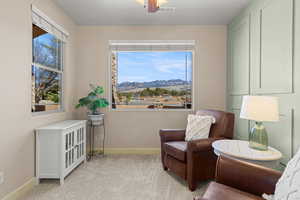 Living area featuring a mountain view, carpet, and a ceiling fan