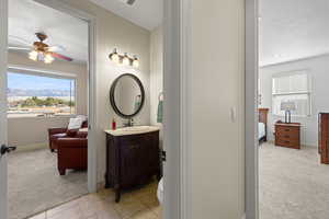 Ensuite bathroom with light colored carpet, a mountain view, vanity, a ceiling fan, and a textured ceiling
