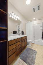 Bathroom featuring vanity, shower / bath combo, and light tile patterned floors