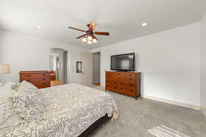 Bedroom with arched walkways, light colored carpet, a ceiling fan, and recessed lighting