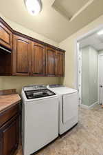 Laundry room with cabinet space, a textured ceiling, and washing machine and dryer