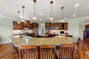 Kitchen with arched walkways, decorative backsplash, a breakfast bar, glass insert cabinets, and recessed lighting