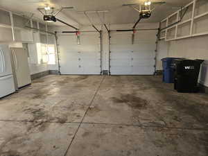 Garage featuring freestanding refrigerator and a garage door opener