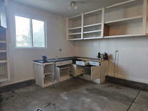 Unfurnished office featuring a workshop area and concrete flooring