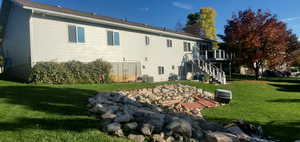 Rear view of property featuring stairs, a lawn, and a deck