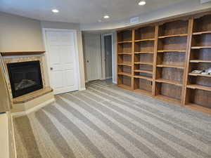 Unfurnished living room with a glass covered fireplace, light carpet, and recessed lighting