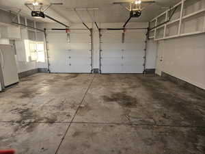 Garage featuring freestanding refrigerator and a garage door opener