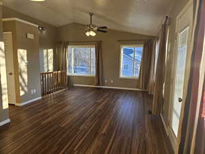 Unfurnished dining area featuring lofted ceiling, dark wood-type flooring, ceiling fan, and a textured ceiling