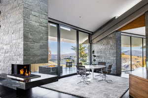 Tiled dining room with a mountain view, a wall of windows, an outdoor stone fireplace, and plenty of natural light