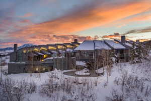 Snow covered back of property with a patio area and a chimney