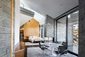Bedroom featuring wood finished floors, a wall of windows, and lofted ceiling