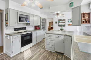 Kitchen with open shelves, range with electric stovetop, a peninsula, stainless steel microwave, and dark wood-style flooring