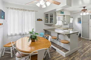 Dining space featuring a ceiling fan and dark wood-type flooring