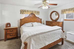 Carpeted bedroom with a ceiling fan and baseboards