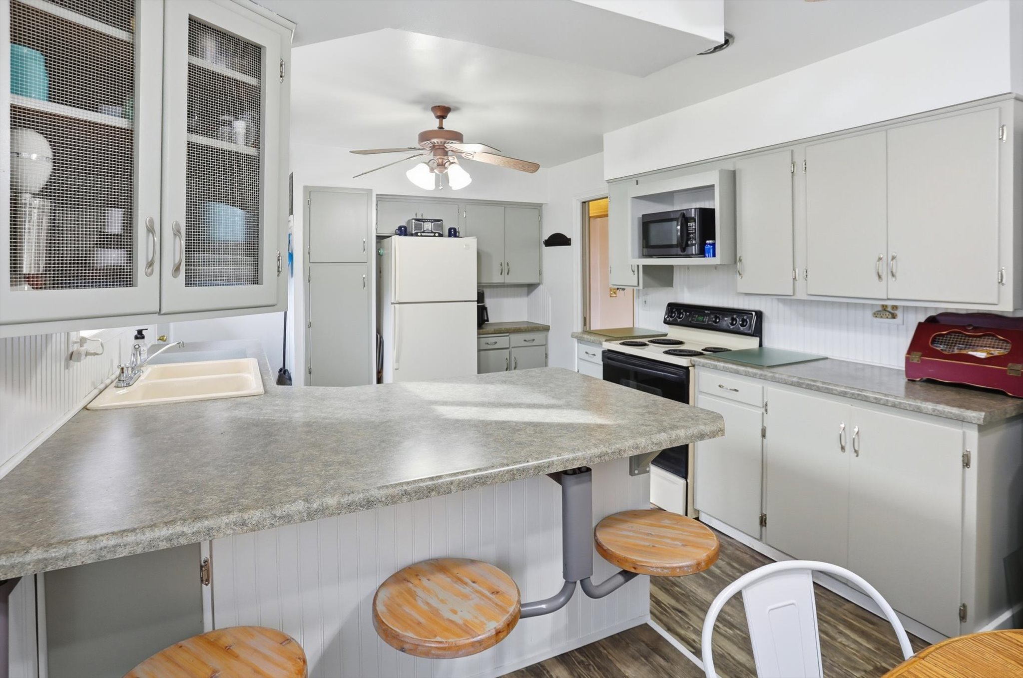 Kitchen featuring a kitchen breakfast bar, a peninsula, freestanding refrigerator, electric range, and dark wood-type flooring