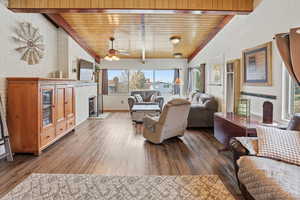 Living area with wood ceiling, wood finished floors, a ceiling fan, and brick wall