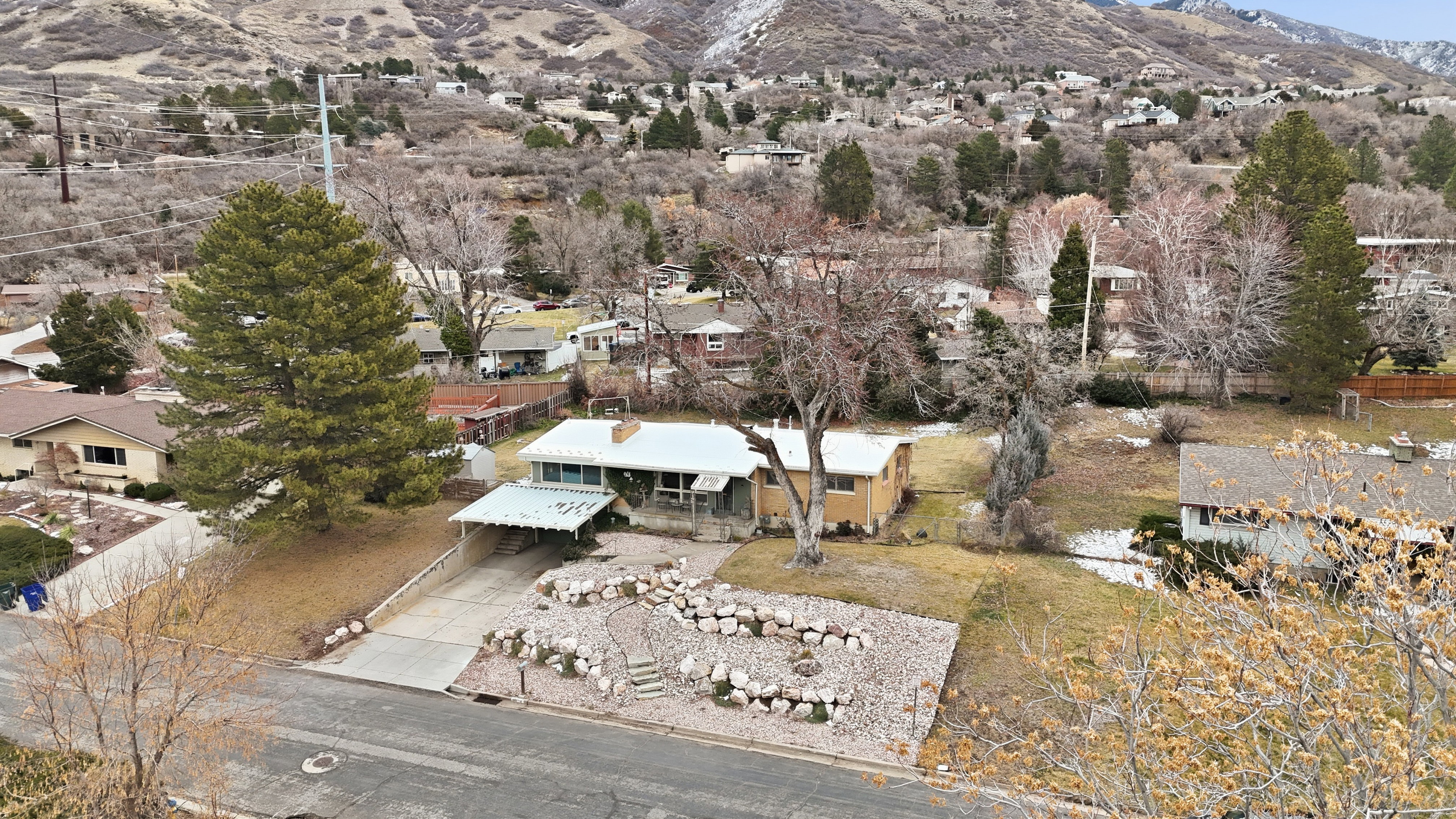 Single-story residence featuring a carport, concrete driveway, and a rock-landscaped front yard