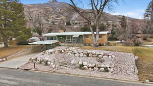 Ranch-style house featuring a chimney, concrete driveway, a mountain view, an attached carport, and brick siding