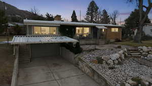 View of front of home with a garage, concrete driveway, a chimney, and a porch