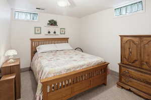Bedroom with multiple windows, a ceiling fan, and light colored carpet