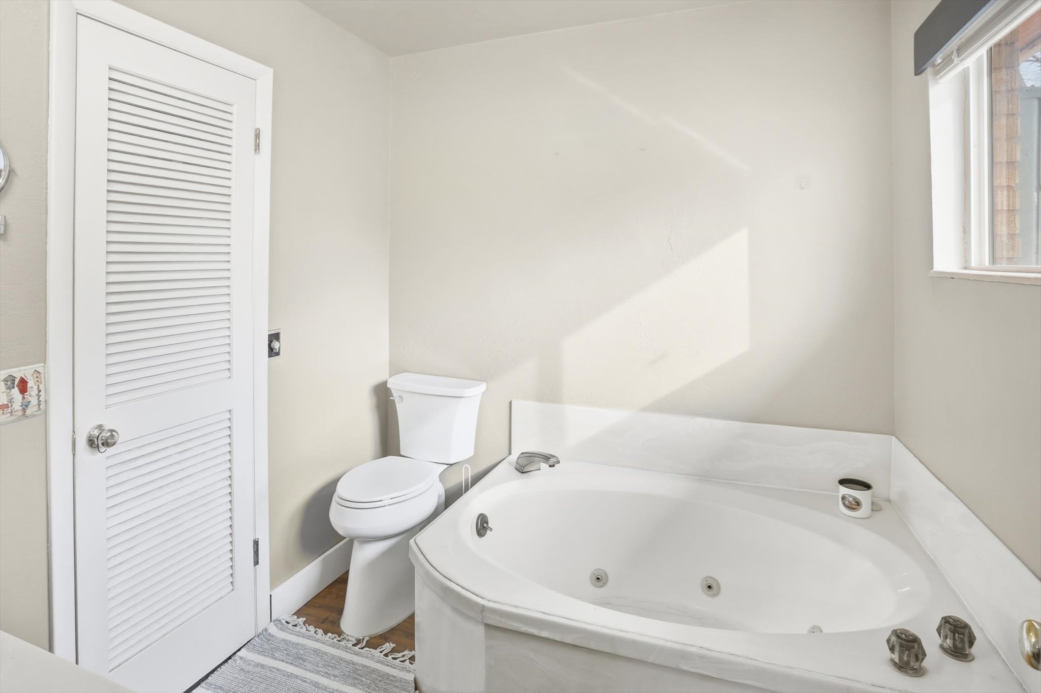 Full bathroom featuring a jetted tub and toilet