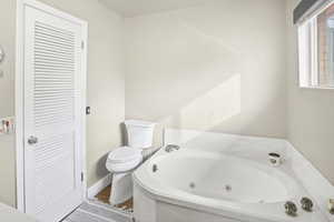 Full bathroom featuring a jetted tub and toilet