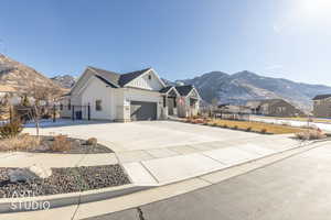 Modern farmhouse featuring a mountain view, driveway, stone siding, a residential view, and board and batten siding