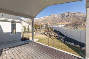 Wooden deck with a fenced backyard and a mountain view