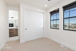 Unfurnished bedroom featuring light colored carpet, a closet, ensuite bath, and recessed lighting